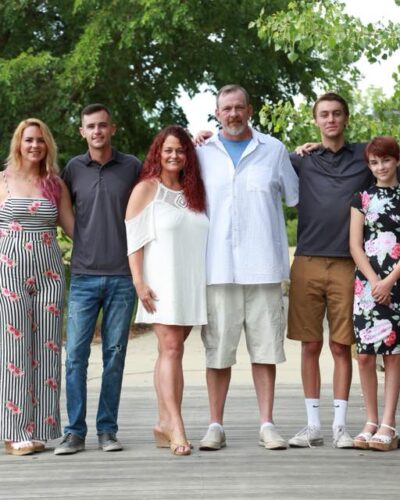 Family posing on wooden bridge outdoors.