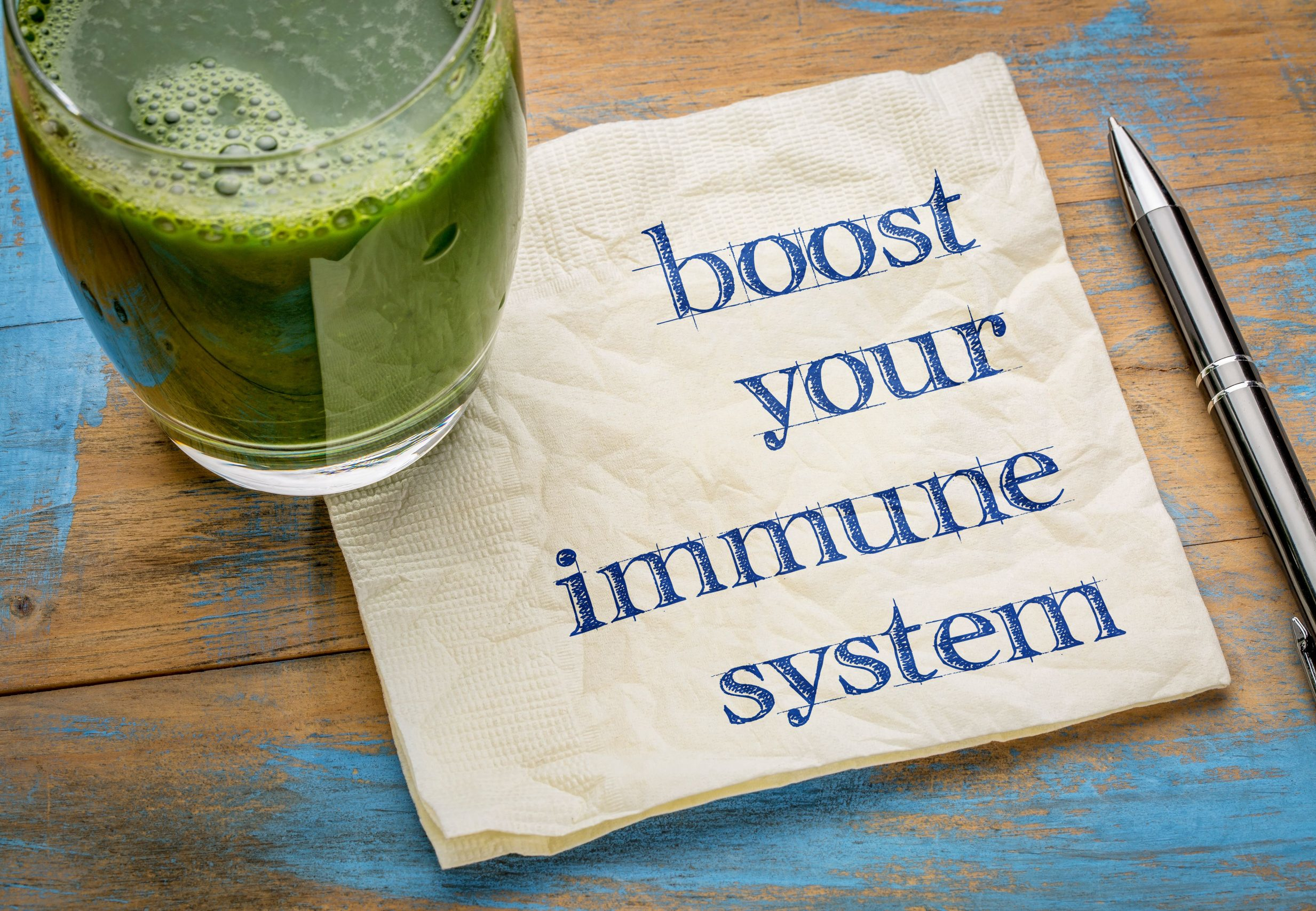 A glass of green juice or tea on top of a napkin that says "boost your immune system"