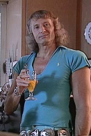 Man in blue shirt holding a drink.